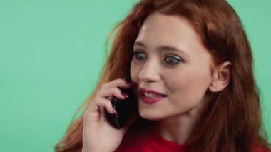 Genç bayan telefonda gülümseyerek konuşur. Gülüyor, şaşırtıcı haberler veriyor ya da dedikodu yapıyor. Kız kucağında ve akıllı telefon kullanıyor. Yeşil stüdyo geçmişi.