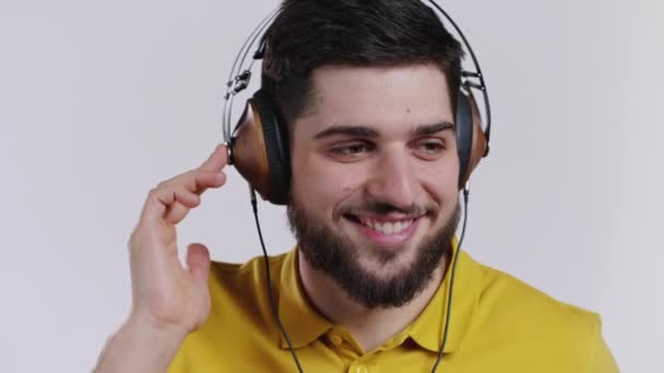 Hombre barbudo escuchando música con auriculares vintage, chico divirtiéndose, sonriendo en el estudio sobre fondo blanco. Danza, concepto de radio. — Vídeos de Stock