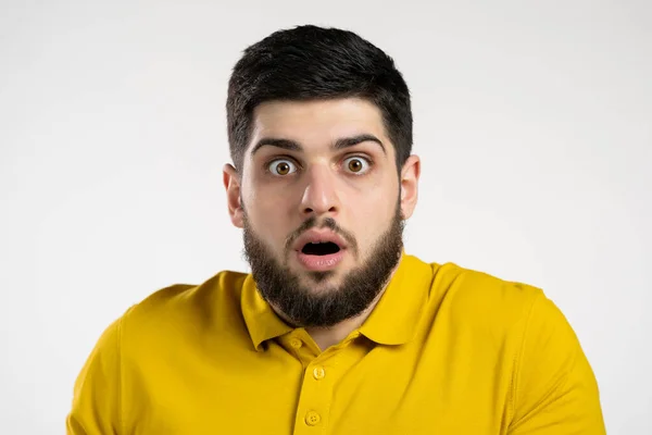 Frightened man afraid of something and looks into camera with big eyes full of horror over white wall background. — Stock Photo, Image