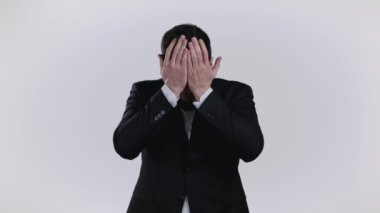 Genç adam gözlerine inanamıyor, onu okşuyor ve beyaz stüdyo arka planında kameraya daha yakından bakıyor. Siyah smokinli şoka uğramış adam..