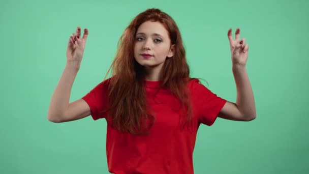 手と2本の指の空気の引用符ジェスチャーを示す赤い髪を持つ美しい女性は、緑の背景に孤立指を曲げる。面白いとか皮肉とか皮肉とかじゃなくて. — ストック動画