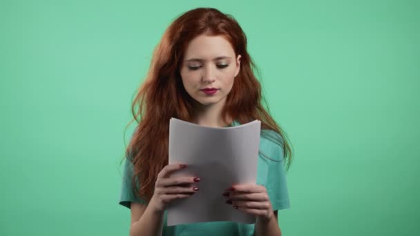 Satisfied woman holding files papers isolated on green background. Pretty girl checks documents, utility bills. — Stock Video