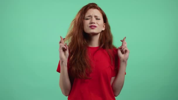 Leuke vrouw biddend met gekruiste vingers op groene achtergrond. Meisje bedelen iemand voldoen aan haar verlangens, helpen met. — Stockvideo