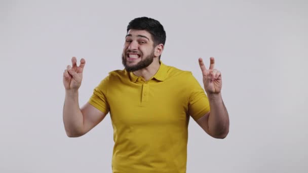 Knappe man met handen en twee vingers lucht citeert gebaar, buig vingers geïsoleerd op witte achtergrond. Een man in het geel. Geen grappig, ironisch en sarcastisch concept. — Stockvideo