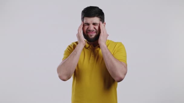 Junger Mann mit Kopfschmerzen, Studioporträt. Guy legt die Hände auf den Kopf, isoliert auf weißem Hintergrund. Problembegriff, Medizin, Krankheit — Stockvideo