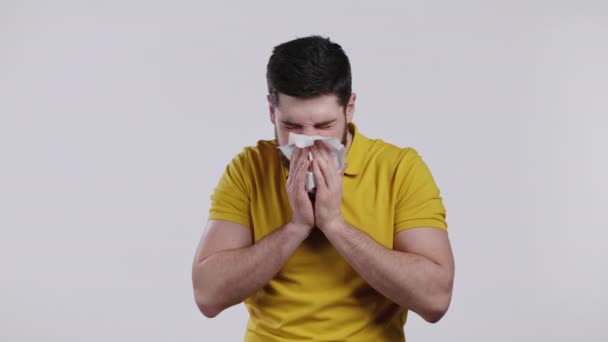 Bärtiger Mann niest in Gewebe. Isolierter Typ auf weißem Studiohintergrund. Er ist krank, hat eine Erkältung oder eine allergische Reaktion. Coronavirus, Epidemie 2021, Krankheitskonzept — Stockvideo