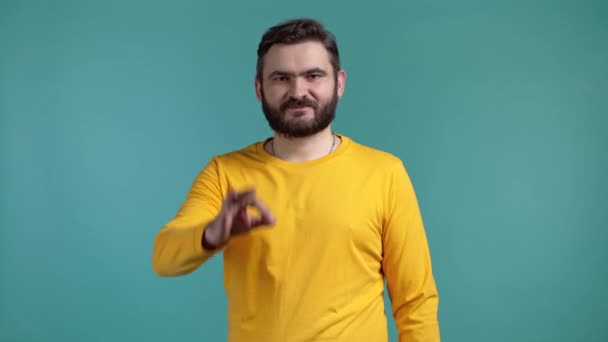 Hombre guapo en ropa amarilla muestra bien, ok gesto. Un tipo feliz sobre fondo azul. Ganador. Éxito. Modelo masculino positivo sonríe a la cámara. Lenguaje corporal. — Vídeos de Stock