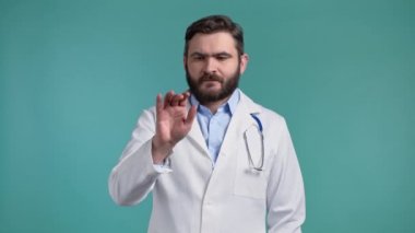 Doktor, mavi stüdyo arka planında görünmez dokunmatik ekran kullanıyor. Tıp önlüklü doktor hava ekranında tıkırdıyor, tıkırdıyor, tıkırdıyor. Teknoloji, tıp arayüzü kavramı.