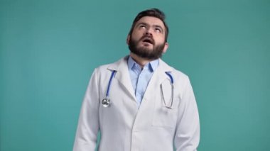 Sıkıcı doktor iç çeker ve gözlerini devirir. Mavi duvar arka planında beyaz önlüklü. Doktor çalışmaktan yoruldu, hayal kırıklığına uğradı, çaresiz kaldı.