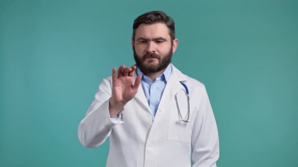 Lekarz używa niewidzialnego ekranu dotykowego na niebieskim tle studia. Lekarz w płaszczu medycznym kradnie, klika, stuka w ekran. Technologia, koncepcja interfejsu medycyny. — Wideo stockowe