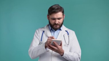 Doktor, hastaların semptomlarını not defterine kaydediyor. Tıbbi beyaz önlüklü doktor mavi stüdyo arka planında yazıyor..