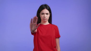 Avuç içi izi olmayan güzel bir kadının onaylamaması Basta 'yı, olumsuzluğu, yeterli jesti yapar. Reddetmek, reddetmek, anlaşmazlık, menekşe arka planda ciddi bir kızın portresi