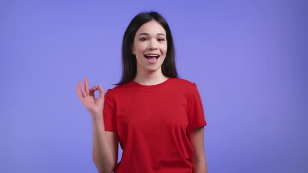 Mulher muito asiática mostrando ok, ok assinar sobre fundo estúdio violeta. Rapariga positiva com cabelo natural sorri para a câmera. Vencedor. Sucesso. Linguagem corporal. — Vídeo de Stock