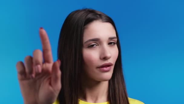 Retrato de mujer seria mostrando gesto de rechazo por señal de stop finger. No juegues conmigo. Chica severa en camiseta amarilla aislada sobre fondo azul. — Vídeos de Stock