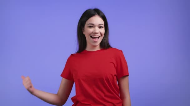 Mulher bonita mostrando o polegar para cima como sinal sobre fundo violeta estúdio. Rapariga positiva com cabelo morena sorri para a câmera. Vencedor. Sucesso. Linguagem corporal. — Vídeo de Stock