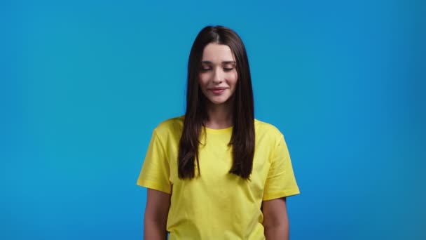 Kvinna visar ja säker tecken, nickar huvudet positivt. Ung dam i gul t-shirt, kroppsspråk koncept. Blå studio bakgrund. — Stockvideo