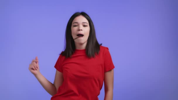 Aantrekkelijke vrouw dansend op violette studio achtergrond. Meisje in rode basic kleding. Positieve stemming. Langzame beweging. — Stockvideo