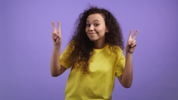 Pretty woman with curly hair showing with hands and two fingers air quotes gesture, bend fingers isolated on violet background. Not funny, irony and sarcasm concept. — Stock Video