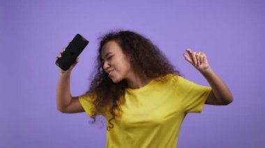 Kablosuz taşınabilir hoparlörden müzik dinleyen kadın - modern ses sistemi. Dans eden kadın, Violet stüdyosunun arka planında eğleniyor. Müziğin ritmine göre hareket eder..
