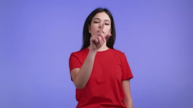 Violet stüdyosunun arka planında görünmez dokunmatik ekran kullanan bir kadın. Kaydırıyor, tıkırdıyor, hava ekranına vuruyor. Teknoloji, arayüz kavramı.