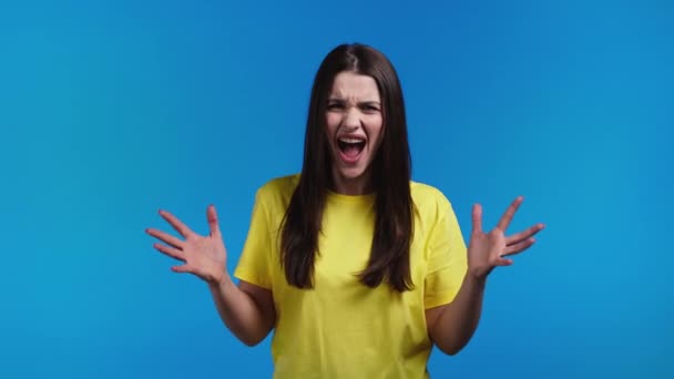 Furious temperamental woman on blue background. Lady in stress and rage, she threatens with aggression, shouting and looking at camera. — Stock Video