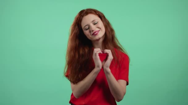 Gentile bella donna che fa segno di forma del cuore vicino al petto. Sfondo verde. Salute delle donne, volontariato, aiuto alla donazione e concetto di amore. — Video Stock