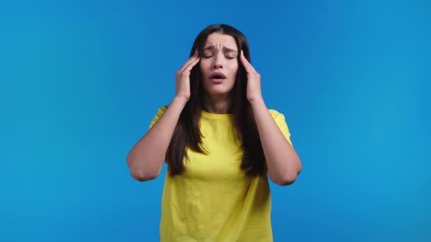 Verveelde vrouw portret, haar hoofd draait rond op een blauwe achtergrond. Mooi meisje is moe van de situatie. Hoofdpijn, migraine concept. — Stockvideo