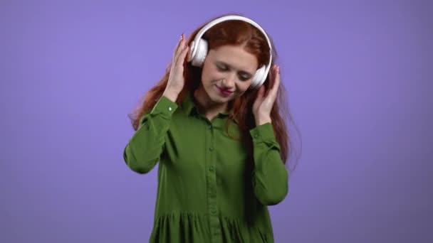 Mooie vrouw met witte koptelefoon op violette studio achtergrond. Schattig meisjes portret. Muziek, radio, geluk, vrijheid, jeugdconcept. — Stockvideo