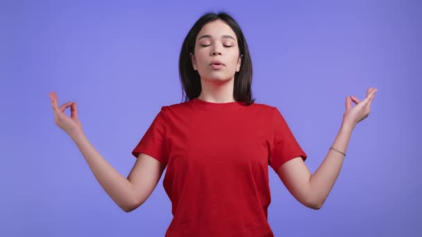 Ruhige Frau, entspannend, meditierend. Sie beruhigt sich, atmet tief durch mit Mudra om auf violettem Studiohintergrund. Yoga-Konzept. — Stockvideo