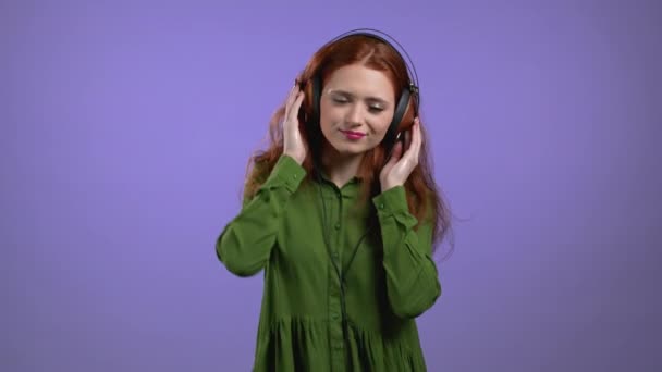 Jolie femme avec écouteurs sur fond violet studio. Joli portrait de filles. Musique, radio, bonheur, danse, concept jeunesse. — Video