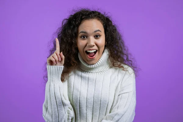 Портрет молодої жінки, яка має момент уявлення, вказуючи пальцем на фіолетовий студійний фон. Посміхаючись щаслива дівчина показує жест єврики . — стокове фото