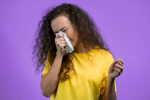 Pretty woman sneezes into tissue. Isolated girl on purple studio background. Lady is sick, has a cold or allergic reaction. Coronavirus, epidemic 2021, illness concept — Stock Photo, Image