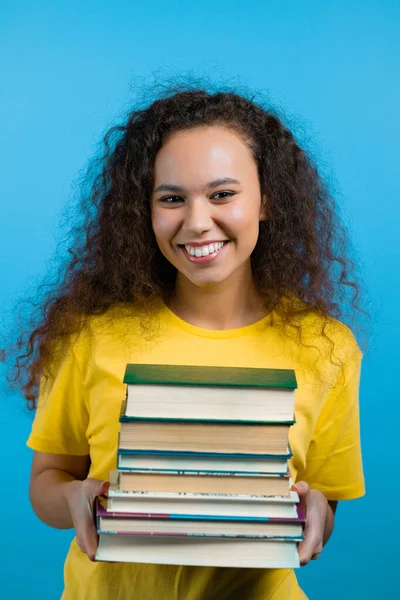 학생들은 스튜디오에 있는 파란 배경의 도서관에서 책들을 쌓아 놓습니다. 웃는 여자, 졸업하게 되서 행복하답니다. — 스톡 사진