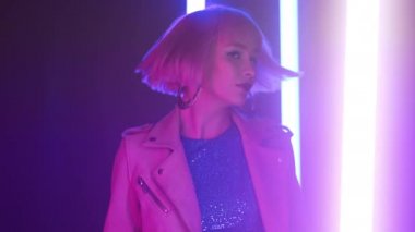 Renkli neon lambalarla boyanmış pembe saç stili dansı yapan şık bir kadın. Moda makyajlı hippi. Gece kulübü, fütüristik kıyafet. Seksi kadın konsepti. 