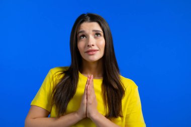 Güzel bir kadın mavi arka plan için dua ediyor. Sarı tişörtlü kız birine arzularını tatmin etmesi için yalvarıyor..