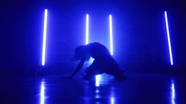 Seksi kıyafetli çekici kadın, uzun lambalı, mavi stüdyodaki müzik eşliğinde dans ediyor. Bayan tek başına gösteri yapıyor. Cinsel dans, koreografi, sanat kavramı