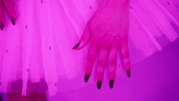 Pełna wdzięku balerina dotykająca ręką swojej sukienki tutu, różowe światło. Kobieta z długimi ciemnymi paznokciami i przewiewną spódnicą. Zdjęcia studyjne. Koncepcja sztuki. — Wideo stockowe