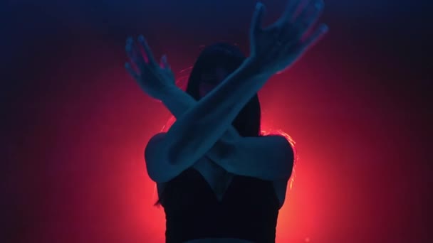Genç bir kadının portresi kollarını stüdyoda hareket ettiriyor. Modern moda. Renkli sahne ışıkları altında dans eden bir bayan. Neon ışıklı cinsel dans kavramı. — Stok video