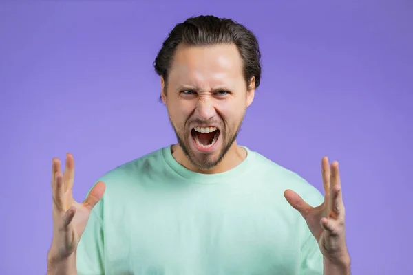 Mann in Rage auf violettem Hintergrund. Europäischer Typ im Stress, er ist aggressiv und blickt mit Hass in die Kamera — Stockfoto