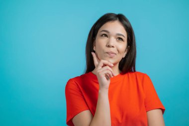 Düşünen kadın mavi stüdyo geçmişine bakıyor. Düşünceli yüz ifadeleri. Çekici görünümlü güzel bir model. 