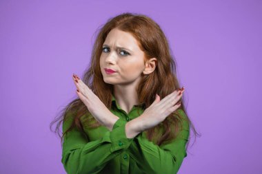 Çapraz el işareti olmadan onaylamayan güzel bir kız Basta, Negatif, bu kadar jest yeter. Reddetmek, reddetmek, anlaşmazlık, menekşe arka planda güzel bir kadının portresi