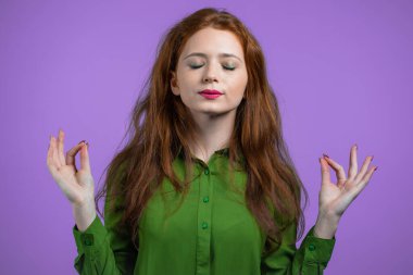 Sakin bir kadın dinleniyor, meditasyon yapıyor. Sakinleşir, Violet 'in stüdyo arka planında derin derin nefes alır. Yoga konsepti.