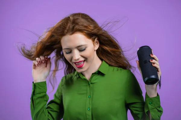 Donna che ascolta musica da altoparlante portatile senza fili - sistema audio moderno. Lady ballare, godendo su sfondo studio viola. Si muove al ritmo della musica. — Foto Stock