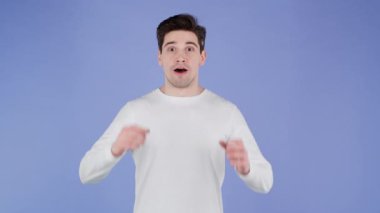 Genç adam çok mutlu ve mutlu, evet gösteriyor. Zafer jesti, başarıya ulaşan adam, hedefler. Mor arka planda heyecanlı ve mutlu bir adam.