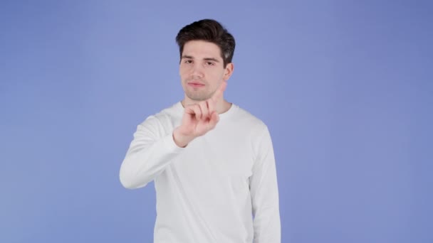Портрет серйозної людини в білому, що показує відкидання жесту знаком стоп-пальця. Не грай зі мною. Хлопець ізольований на фіолетовому фоні . — стокове відео