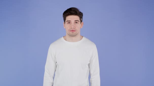 Portret van een knappe man met witte lange mouwen die naar de camera kijkt. Guy in studio op heldere paarse achtergrond. — Stockvideo