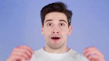 Genç adam çok mutlu ve mutlu, evet gösteriyor. Zafer jesti, başarıya ulaşan adam, hedefler. Mor arka planda heyecanlı ve mutlu bir adam.