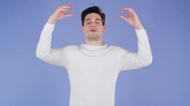 Beyazlı sakin adam dinleniyor, meditasyon yapıyor. Sakinleşir, mor stüdyo arka planında derin derin nefes alır. Yoga konsepti.