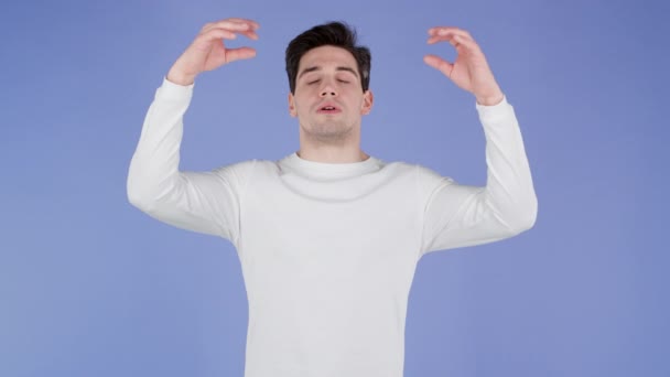 Kalme man in het wit dragen ontspannen, mediteren. Hij kalmeert, ademt diep met mudra om op paarse studioachtergrond. Yoga-concept. — Stockvideo