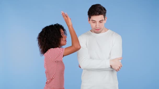 Молодая африканская женщина эмоционально кричит на мужа или парня на синем фоне. Скучный мужчина в белом. Концепция конфликта, проблемы в отношениях, Межрасовая пара. — стоковое видео
